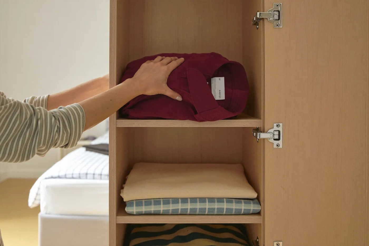 Hände räumen Kleidung in einen Schrank ein